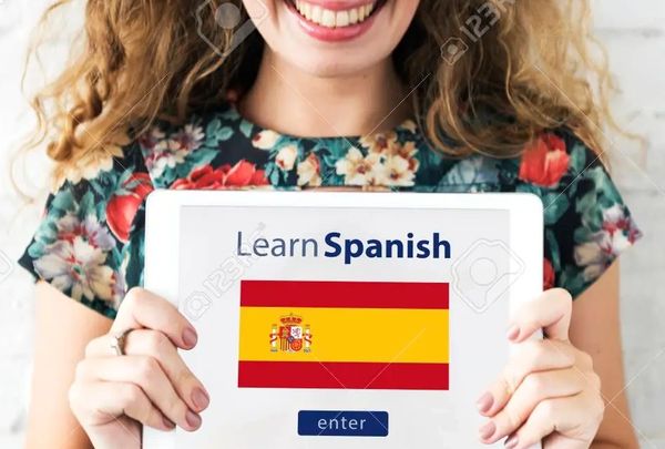 a beautiful young woman holding a sign to learn Spanish as a language; along with flag of  Spain