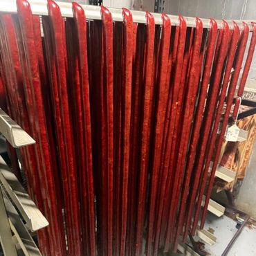 Rows of polished red wooden skis standing upright on a rack indoors.