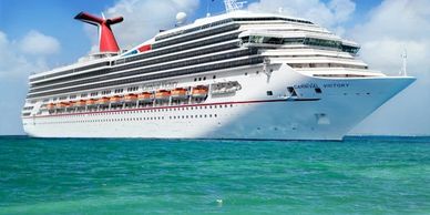 Large white cruise ship sailing on clear blue ocean under sunny sky.