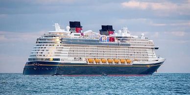 Large cruise ship sailing on calm sea under cloudy sky.