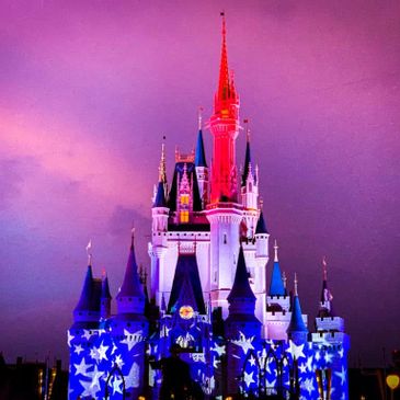 A brightly lit castle with star patterns against a purple sky at dusk.