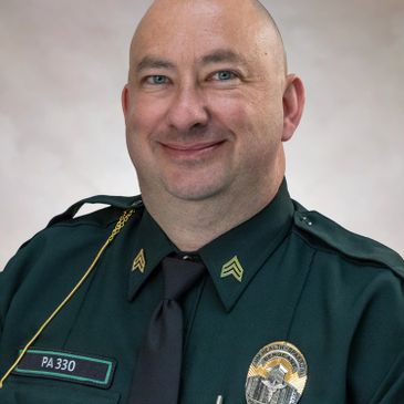 Portrait of a smiling police officer in uniform with badges and insignia.