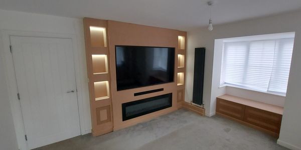 Modern living room with wall-mounted TV, built-in shelves, and window seat with storage.