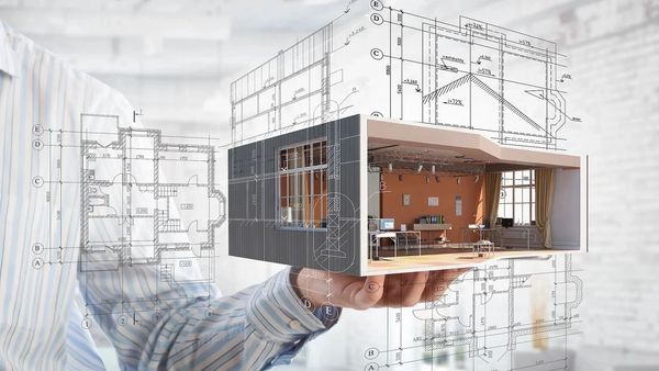 Hand holding a 3D architectural model of a modern office space with blueprints in the background.