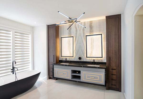 Modern bathroom with black bathtub and double vanity under illuminated mirrors.
