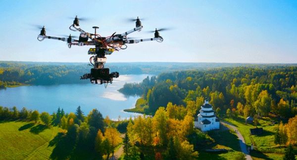 A drone flying over a scenic landscape with a lake and greenery.