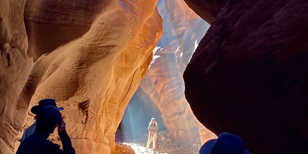 woman standing in beam of light inside chamber of slot canyon buckskin gulch