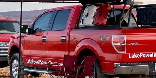 Red suburban and red truck parked for Lake Powell Scenic Tour's sunset tour.