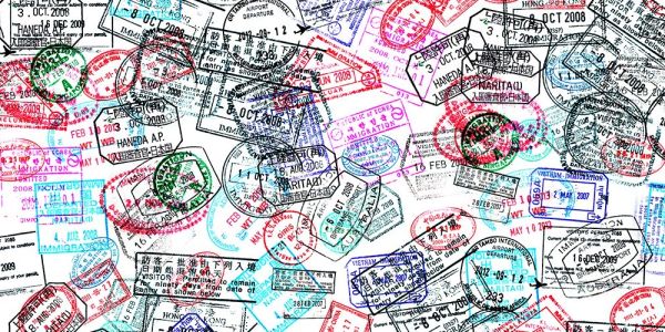 Colorful overlapping passport stamps from various countries.