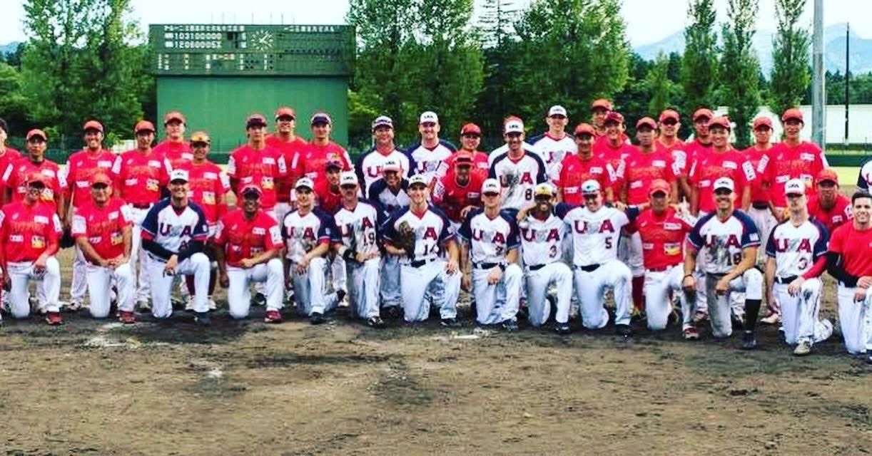 A large group of baseball players in red and white USA uniforms posing together.