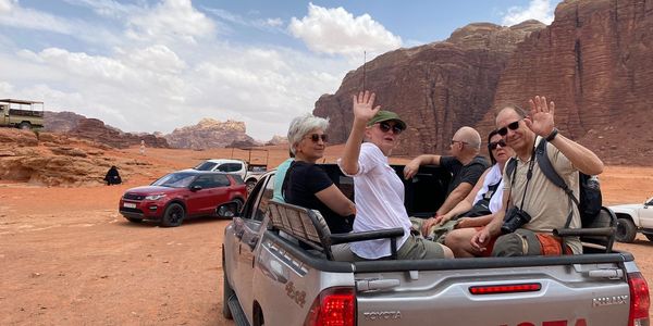 Group of tourists in a Toyota pickup in a desert landscape with rocky formations.