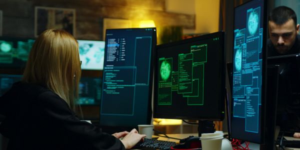 Two programmers working on cybersecurity with multiple monitors displaying code and brain scans.