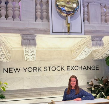 Woman standing in front of a sign that says New York Stock Exchange