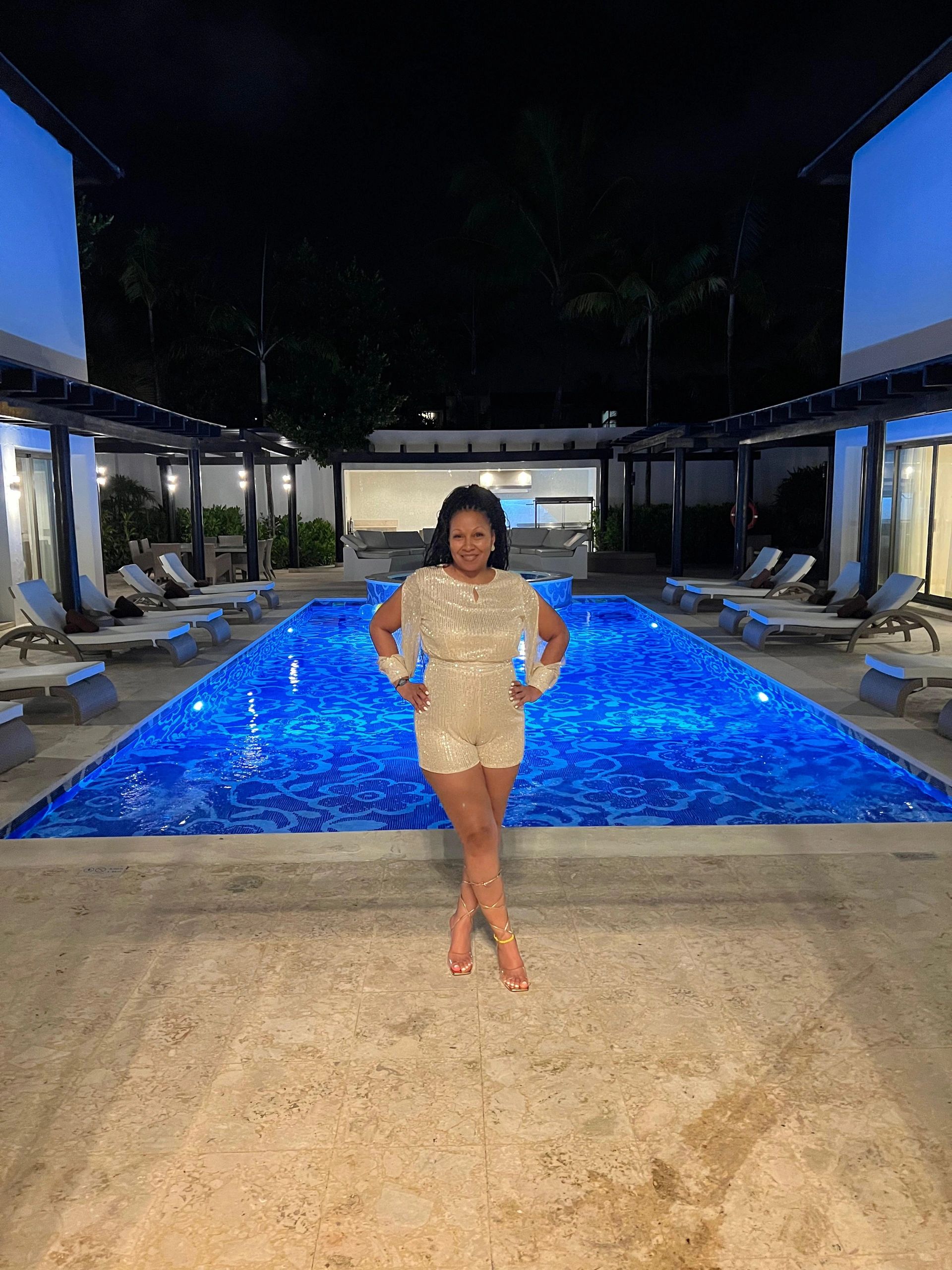 Teressa standing poolside outside a luxury mansion