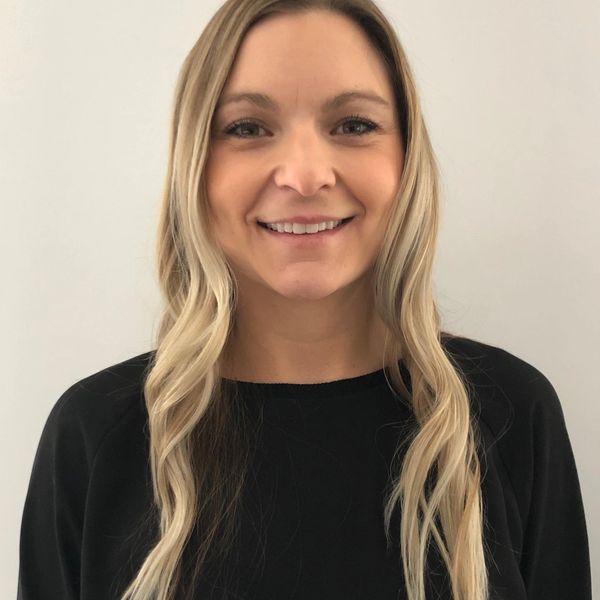 Smiling woman with long blonde hair wearing a black top.