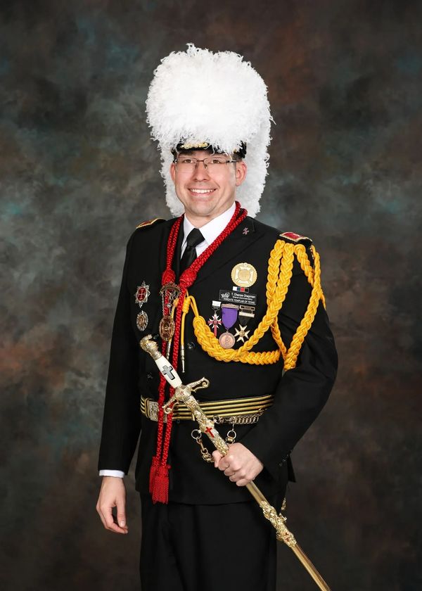Man in elaborate ceremonial military uniform with white plume and medals.