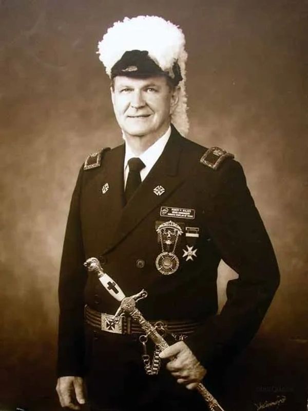 Portrait of a man in ornate ceremonial military uniform with a plumed hat and decorated sword.