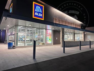Night view of an illuminated Aldi store entrance with modern design and clear signage.