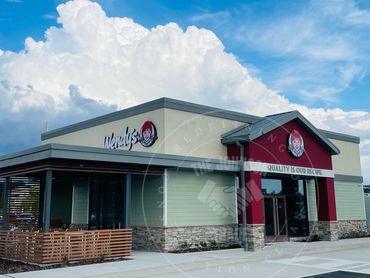 Modern Wendy's restaurant under a blue sky with large clouds.