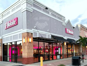 T-Mobile store with bright pink interior lighting and glass windows at dusk.