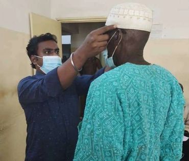 A man checks another man's temperature with a thermometer indoors.