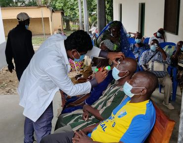 Healthcare worker treats patients in a clinic setting with face masks.