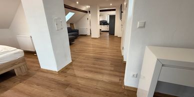 Spacious attic apartment with wooden flooring and modern furnishings.