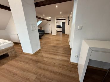 Spacious attic apartment with wooden flooring and modern furnishings.