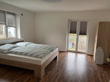 Minimalist bedroom with wooden flooring, double bed, and wardrobe.
