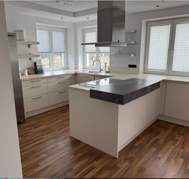 Modern kitchen with white cabinets, wood flooring, and a black countertop island.