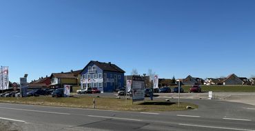 Car dealership with a blue building and clear sky.
