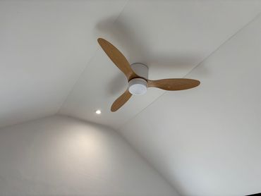 Minimalist ceiling fan with wooden blades on a white ceiling.