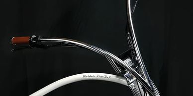 Close-up of a stylish white cruiser bike with chrome handlebars against a black background.