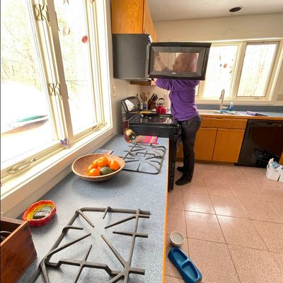 A woman cleaning the microwave oven in a kitchen