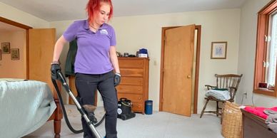 A woman cleaning cleaning the carpet using the vacuum