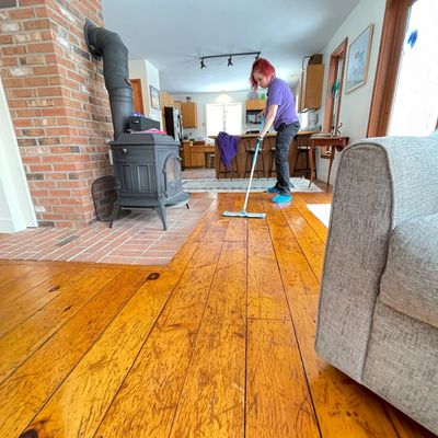 A woman cleaning the wooden floor of a home