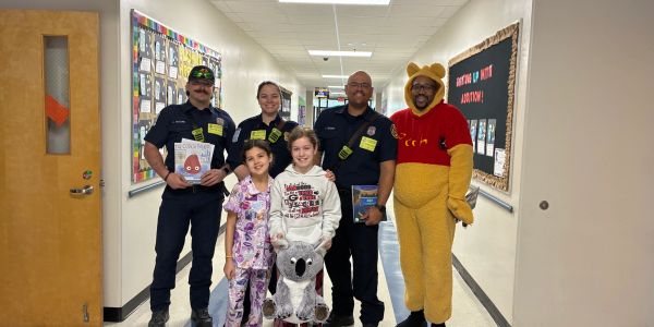 Group photo with kids, police officers, and a person in a Winnie the Pooh costume.