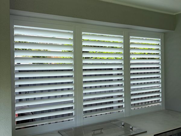 White plantation shutters covering three large windows.