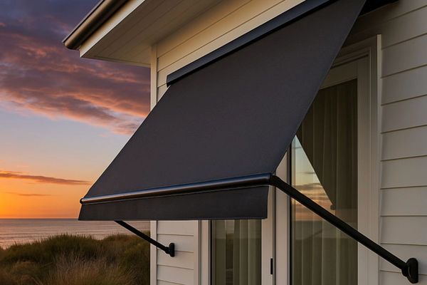 Black fabric awning on a house window at sunset by the sea.