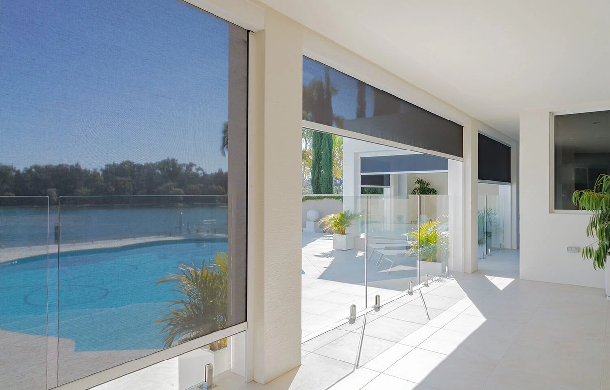 Modern patio with motorized screens overlooking a pool and lake view.