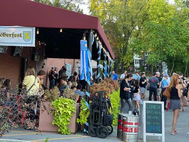 People enjoying an Oktoberfest celebration outdoors with festive decorations.