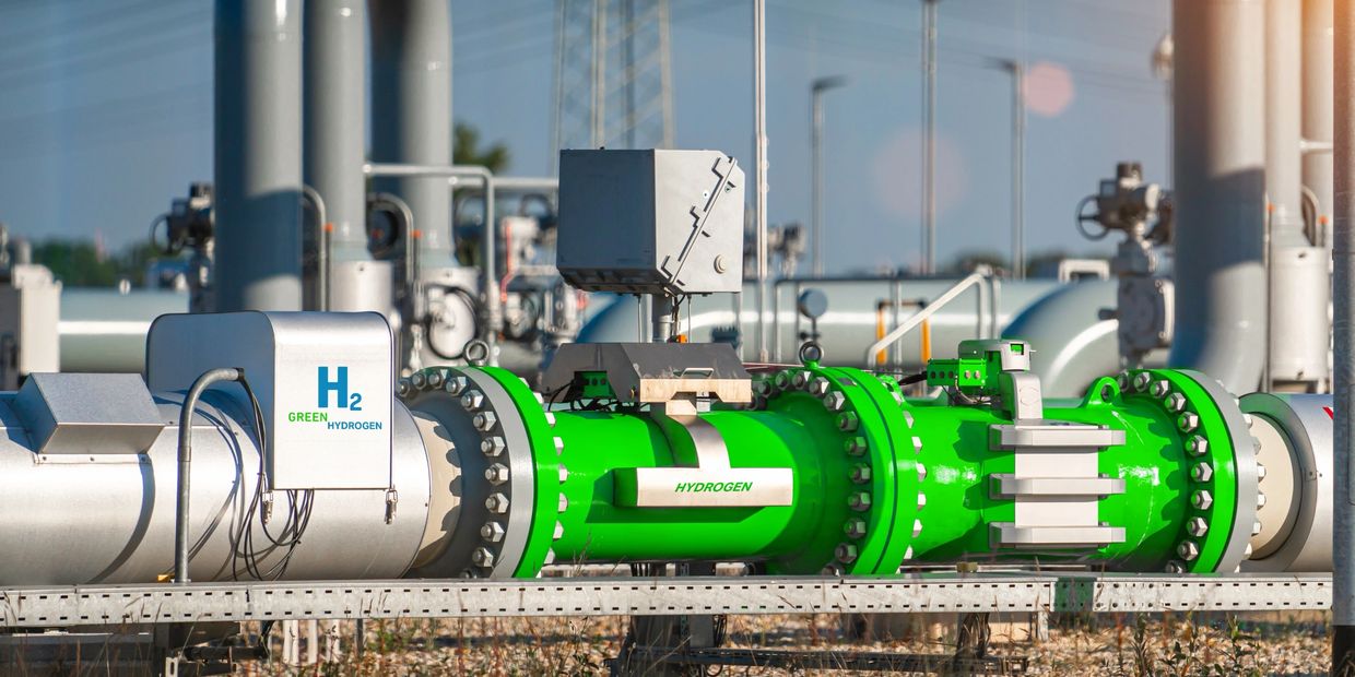 Green hydrogen pipeline infrastructure with metallic and green pipes.