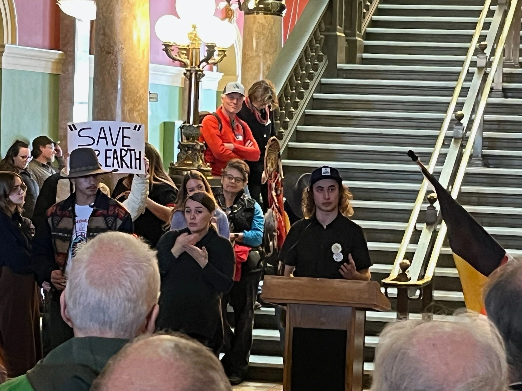 Luca speaks from a podium in the Montana State Capitol Rotunda at Climate Advocacy Day 2025.