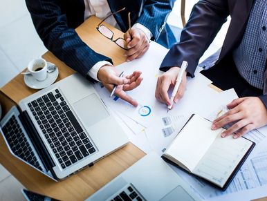 The business team is working with the plan on the desk and the modern laptop