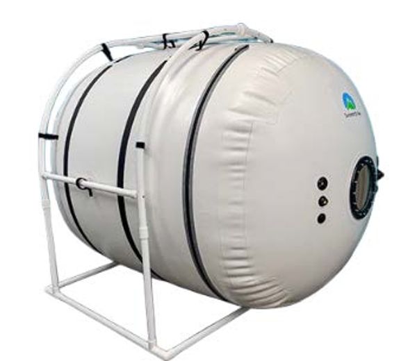 A large, white hyperbaric oxygen therapy chamber on a metal frame.