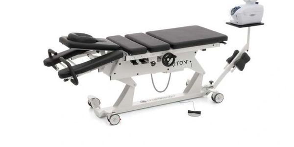 Modern chiropractic adjustment table with electronic control and padded sections.
