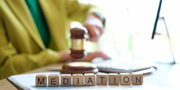 Wooden blocks spelling 'MEDIATION' with a judge's gavel in the background.