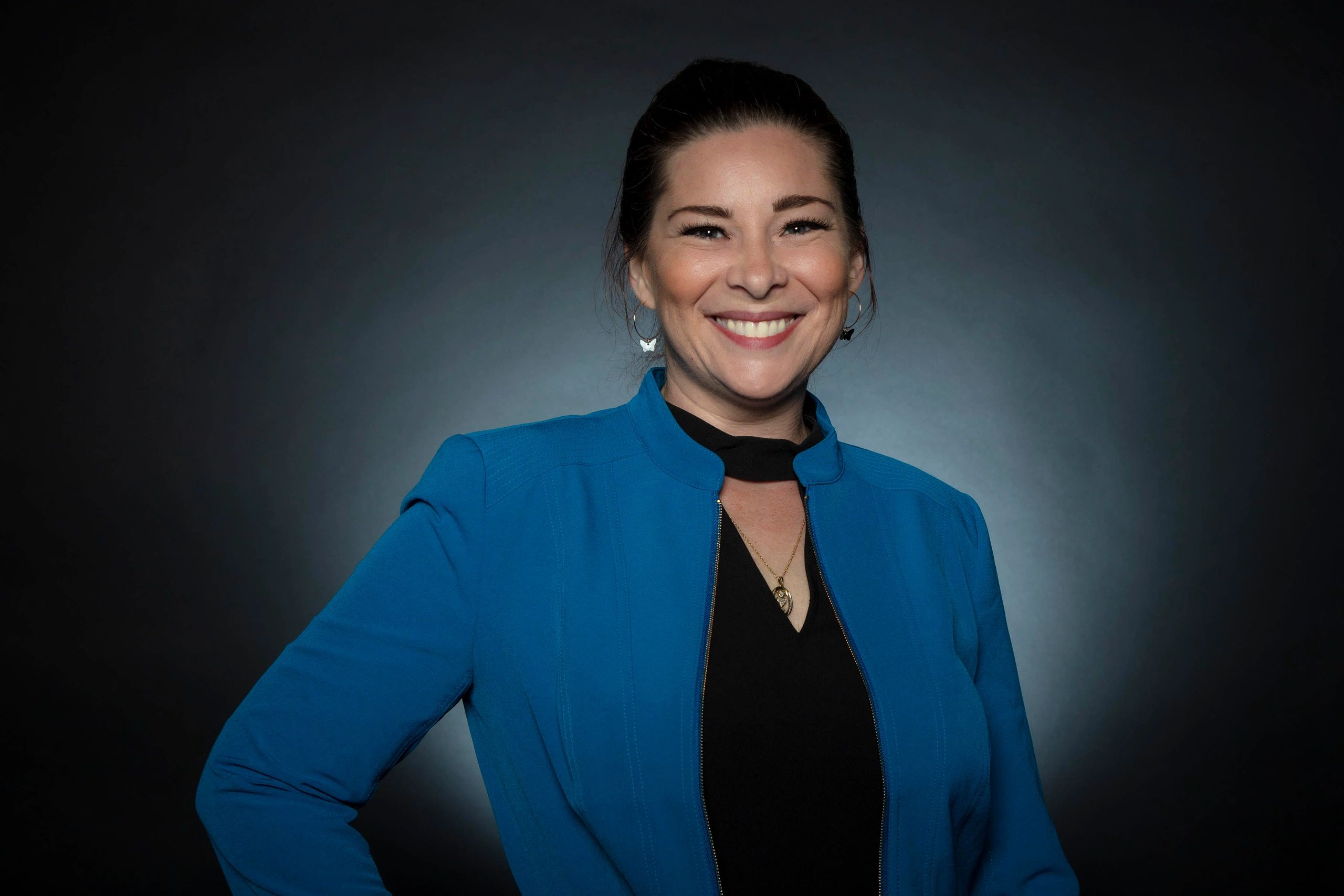 Professional Female Coach with a big smile and wearing a blue jacket and black top