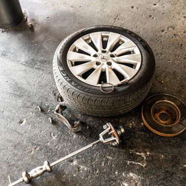 Car wheel and various mechanical parts on a rough floor surface.