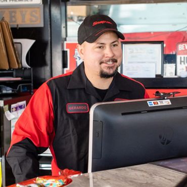 Smiling man named Gerardo in a Snap-on uniform working at a counter with a computer.